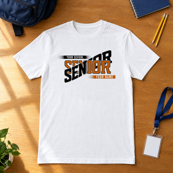 White custom Senior class year shirt in burnt orange and black laid flat on a wood desk with a school backpack, notebook, pencils and ID lanyard