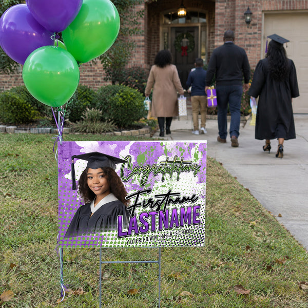 Custom graduation yard sign in a front yard with balloons as family arrives for the celebration