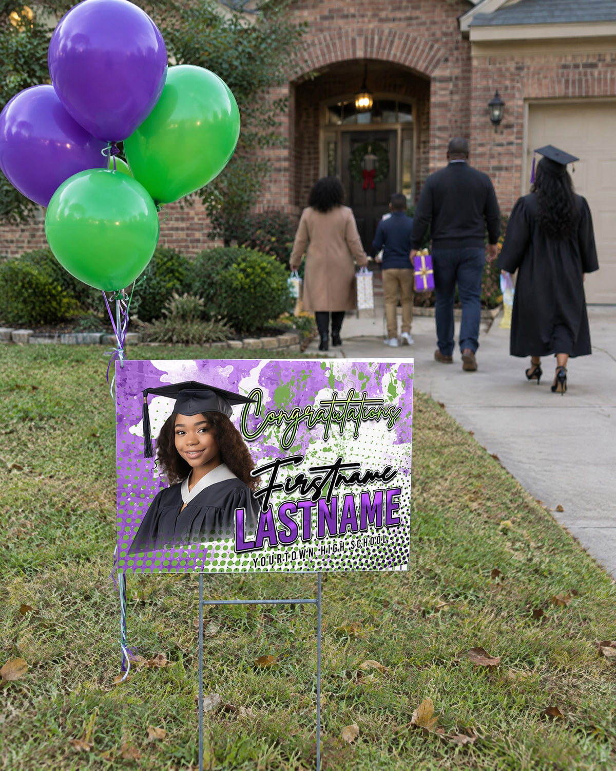 Custom graduation yard sign in a front yard with balloons as family arrives for the celebration