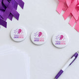 Domestic Violence and Breast Cancer Awareness sublimation buttons on a fundraiser table with purple and pink ribbons