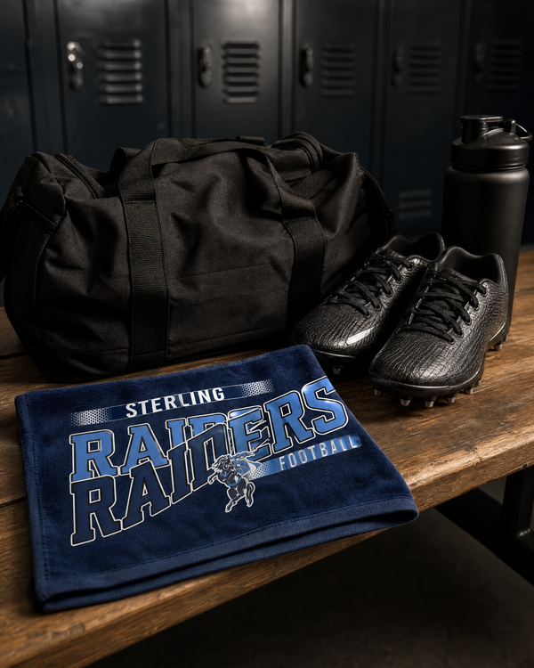 Navy game day rally towel with a football team design folded on a locker room bench beside a gym bag and cleats.