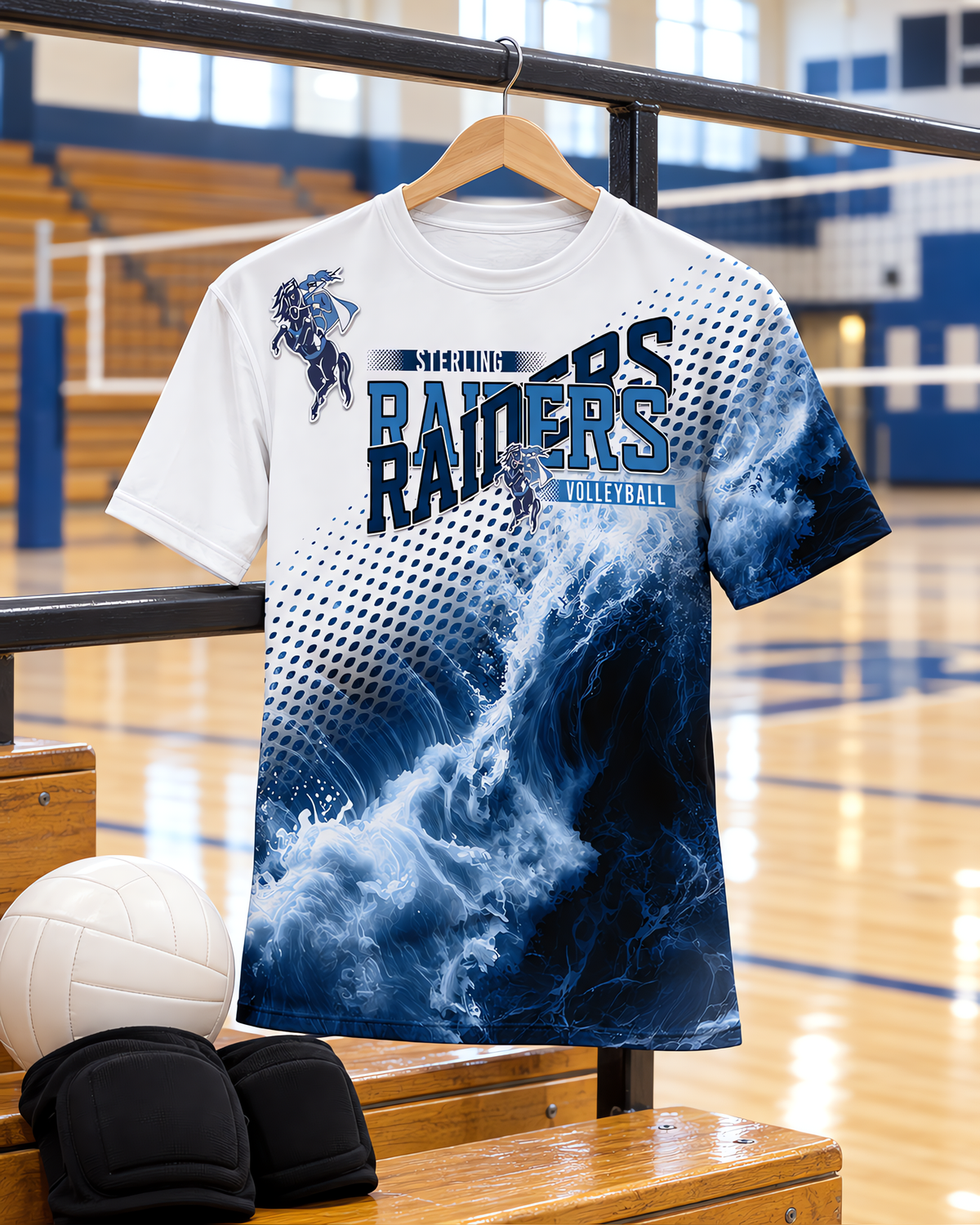 All over volleyball spirit shirt on a hanger on the gym bleacher railing above a volleyball and knee pads.