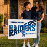 Navy and light blue game day yard sign on a stake in a front yard by a brick home at golden hour, with a mom and her son.