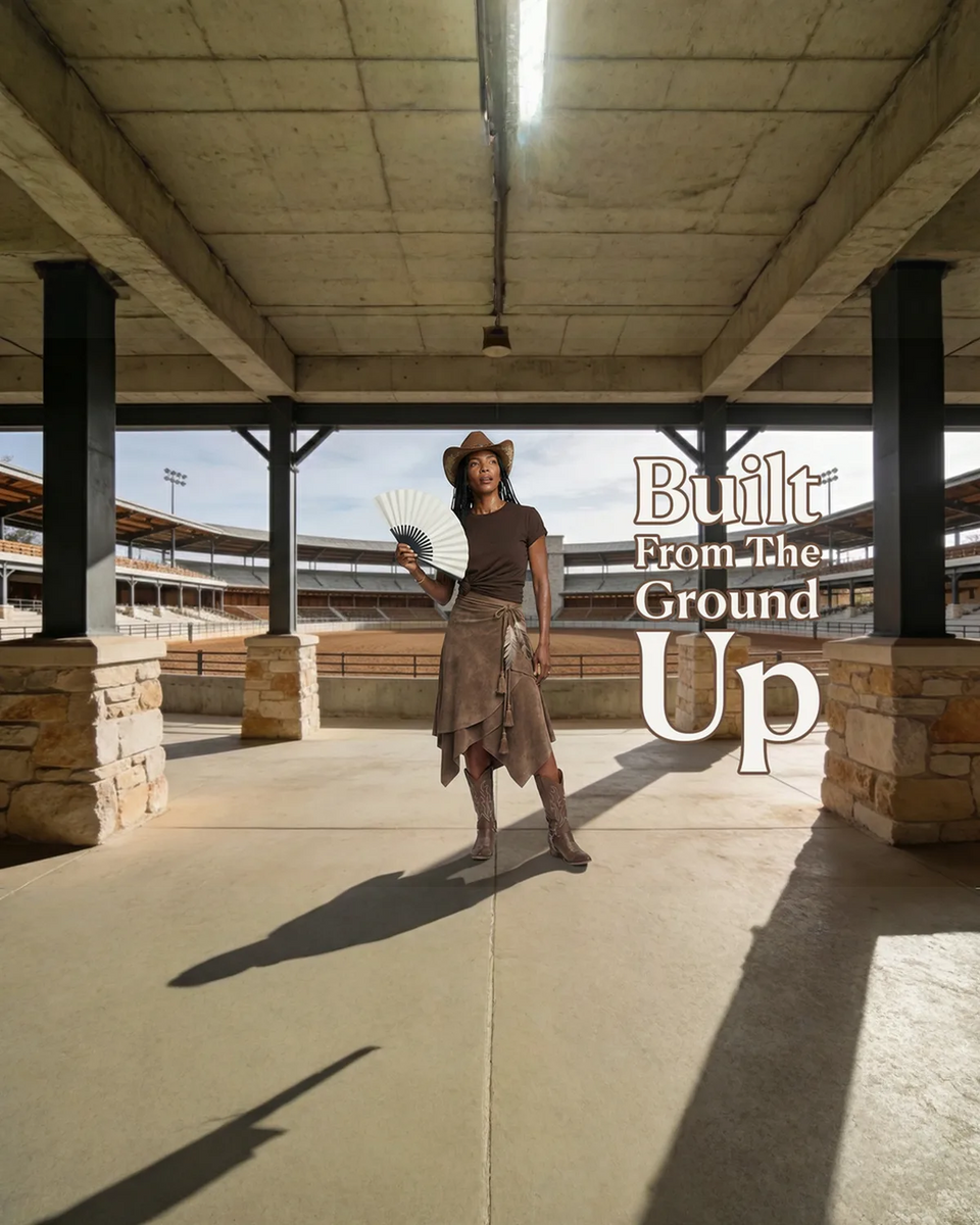  Woman in a cowboy hat and suede skirt holding a folding hand fan at a rodeo arena