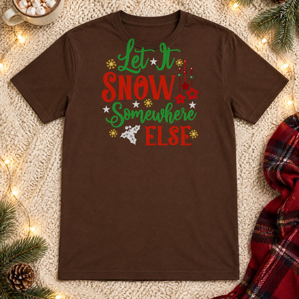 Let It Snow Somewhere Else brown graphic tee flat lay with hot cocoa, string lights and a plaid scarf