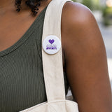 Love Shouldn't Hurt 2.5 inch sublimation button pinned on a canvas tote strap