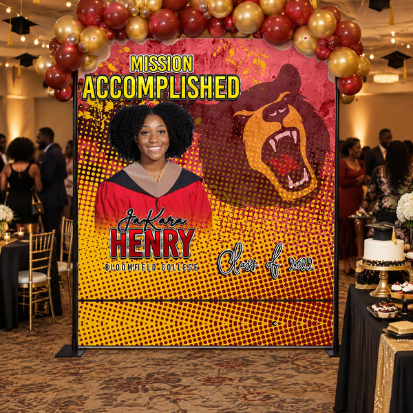 Mission Accomplished graduation backdrop with a red and gold balloon garland at a graduation party