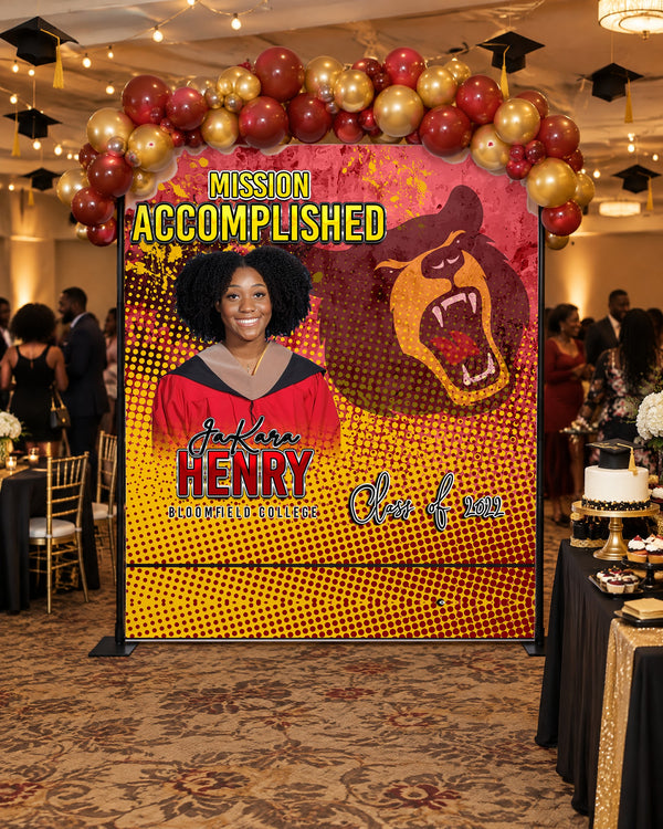 Mission Accomplished graduation backdrop with a red and gold balloon garland at a graduation party