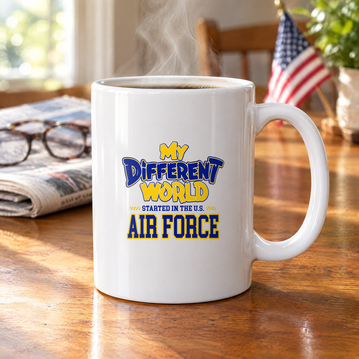 My Different World Started in the U.S. Air Force coffee mug with hot coffee on a wooden kitchen table, with reading glasses, a newspaper and a small American flag