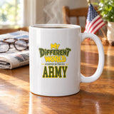 My Different World Started in the U.S. Army coffee mug with hot coffee on a wooden kitchen table, with reading glasses, a newspaper and a small American flag