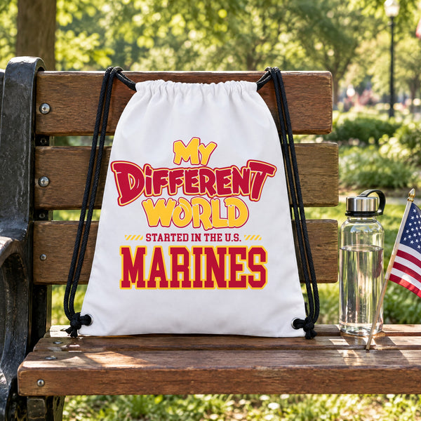 My Different World Started in the U.S. Marines white drawstring backpack hanging on a wooden park bench, with a water bottle and a small American flag