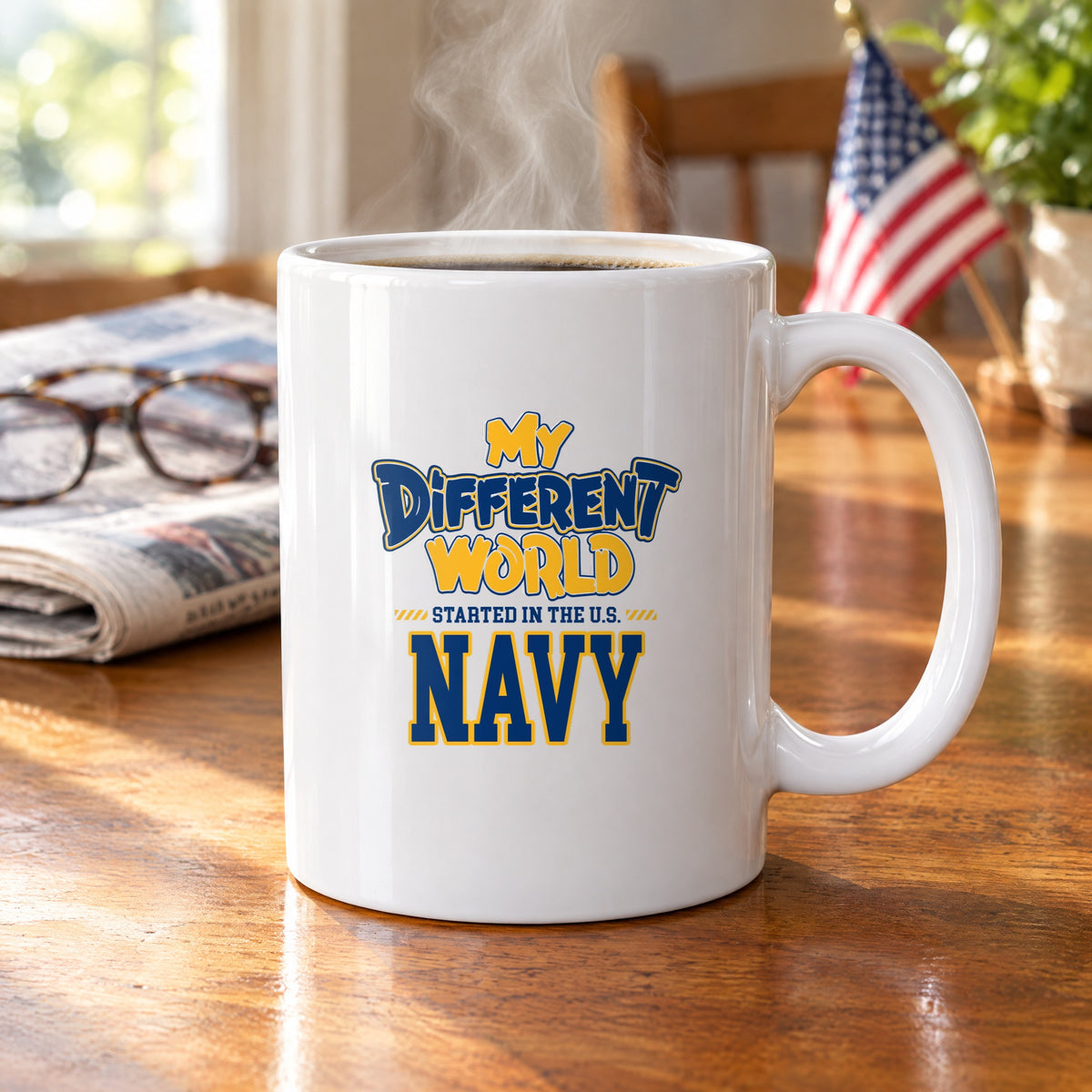 My Different World Started in the U.S. Navy coffee mug with hot coffee on a wooden kitchen table, with reading glasses, a newspaper and a small American flag